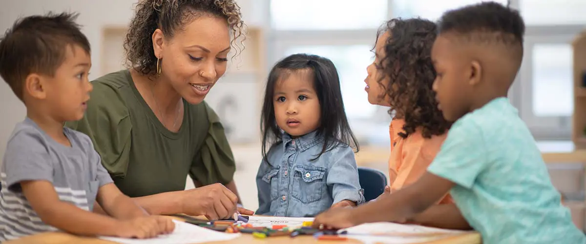 A daycare employee reading a book to a group of children.