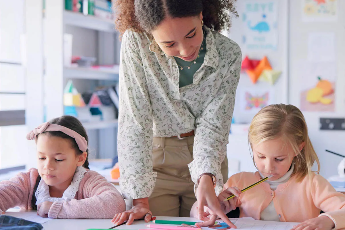 A teacher helps young children in a classroom. Teachers and other mandated reporters in Pennsylvania can find online Child Abuse Recognition and Reporting training on the Mandated Reporter Training platform.