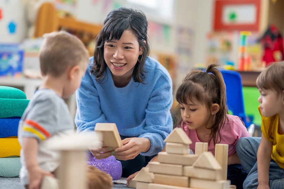 A California child care worker who has taken AB 1207 mandated reporter training plays with young children in a daycare.